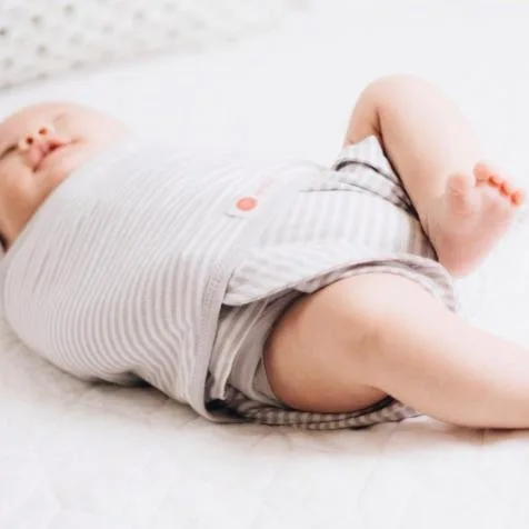 An infant asleep in an Embe Babies swaddle.