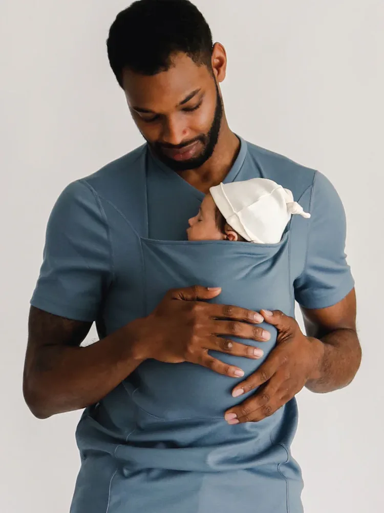 A parent wearing a Lalabu babywearing shirt with a newborn resting in the built-in carrier.